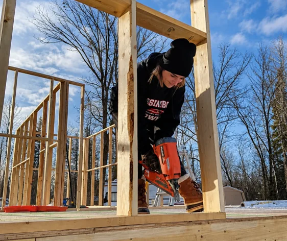 Steph framing a wall with a nail gun