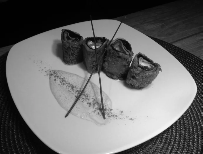 Sushi rolls plated with a scattering of black pepper